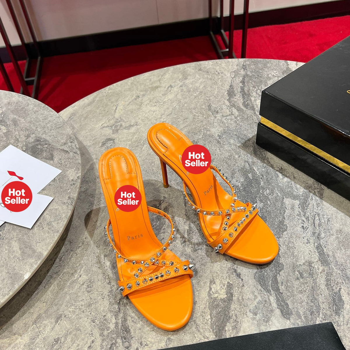Orange high-heeled mules with studded crisscross straps; 10cm heel.