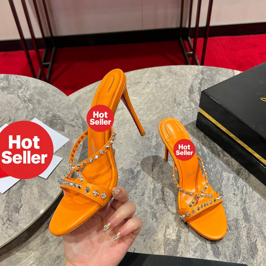 Orange high-heeled mules with studded crisscross straps; 10cm heel.